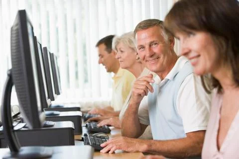 Four people sitting at computer terminals (selective focus/high key) Stock Photos