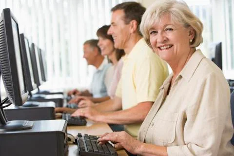 Four people sitting at computer terminals (depth of field/high key) Stock Photos
