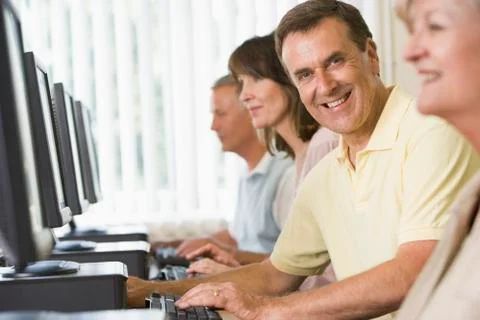 Four people sitting at computer terminals (selective focus/high key) Stock Photos