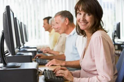Four people sitting at computer terminals (depth of field/high key) Stock-Fotos