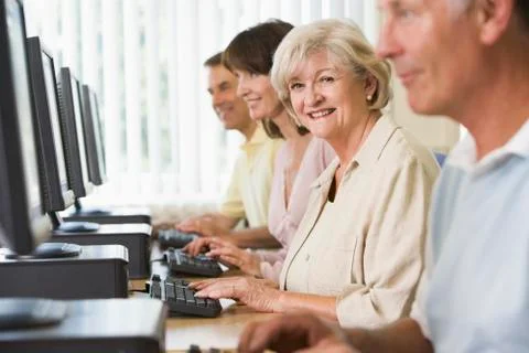 Four people sitting at computer terminals (selective focus/high key) Stock Photos