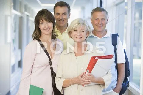 Four people standing in corridor with books (high key) Stock Photos