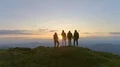 The four people standing on the mountain on a sunrise background 4k or 4k+ Resolution