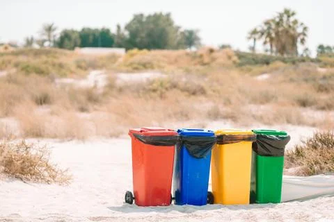 Four plastic containers for garbage sorting on the beach. Stock Photos