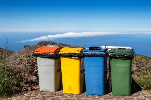 Four plastic containers for garbage at the top of the mountain against the bl Stock Photos