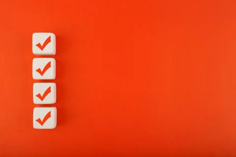 Four red checkmarks on white cubes in a row against red background with copy Stock Photos
