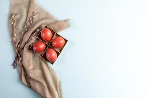 Four red Easter eggs in box with willow branches on beige textile on pale b.. Stock Photos