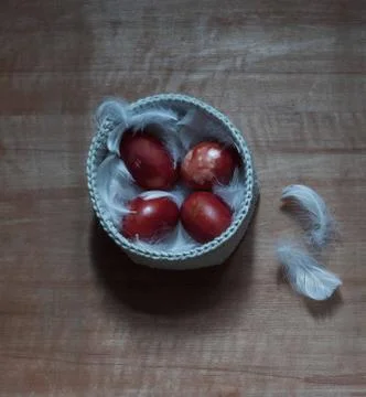 Four red easter eggs on white feathers in a knitted basket 库存照片