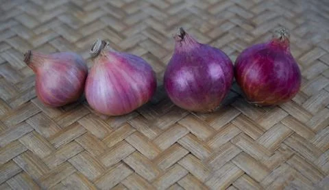 Four red medium sized onion placed beautifully in a line on a wooden backgrou Stock Photos