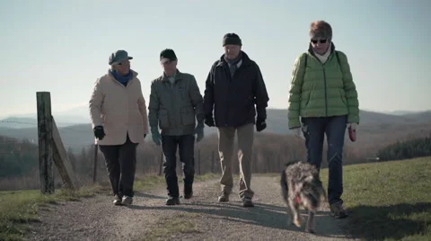 Four retirees walking on path in rural landscape Stock Footage 57841585