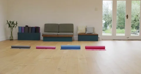 Four rolled up yoga mats in empty studio with wooden floor and doors to garden Stock Footage 339160207