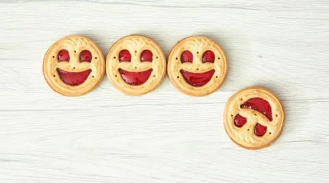 Four round biscuits smiling faces, one of them falls down Stock Photos