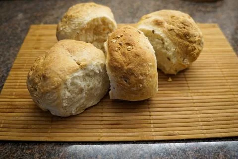 Four Rustic Fresh Bread Rolls on Bamboo Mat Stock Photos