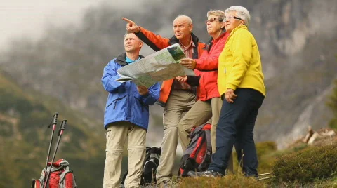 Four senior hikers looking into distance with map Stock Footage