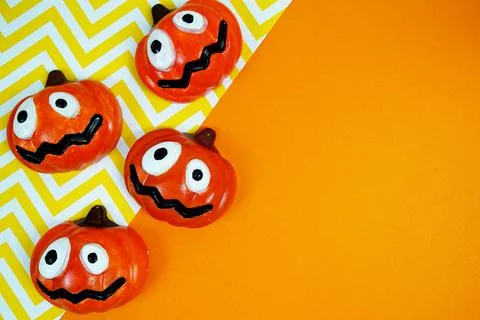Four silly-faced pumpkins lined up against a bright orange and yellow chevr.. Stock Photos