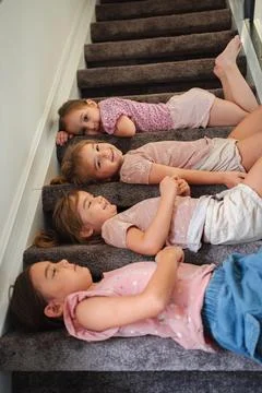 Four Sisters Lying Down on Carpeted Stairs, Bonding and Relaxing at Home Stock Photos