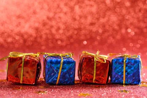 Four small gift boxes in row on red shiny background Foto stock