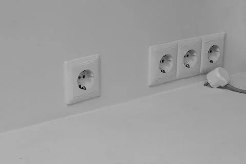 Four sockets on a light wall and one electric plug with a wire. Stock Photos