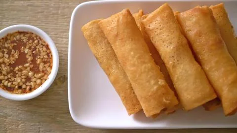 Four spring rolls with dipping sauce on a white plate Stock Photos