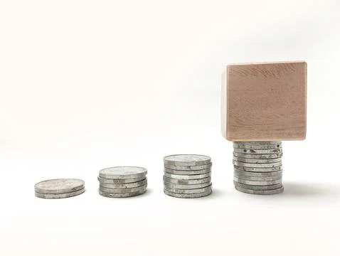 Four stacks of silver coins in increasing height with a blank wooden block .. Stock Photos