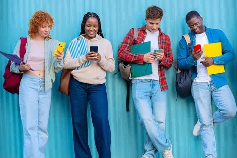 Four students having fun with mobile phones creating content on social media. Stock Photos