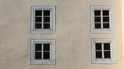 Four symmetrical white-framed windows on a cream plaster wall, Stock Photos