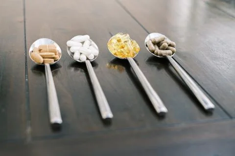 On four tablespoons there are different tablets and pills Stock Photos