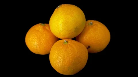Four tangerines rotate on a black background. . Close-up. Stock Footage 118964669