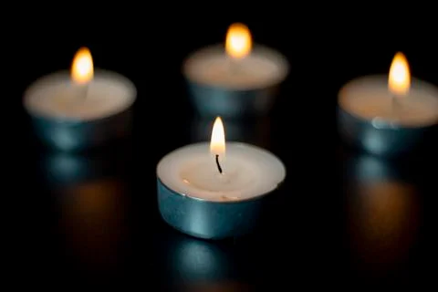 Four tea candles with reflection on black Stock Photos