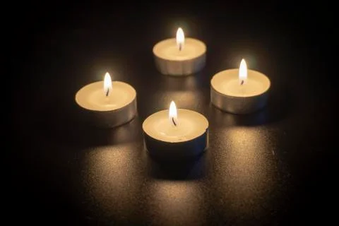Four tea candles with reflection on black Stock Photos