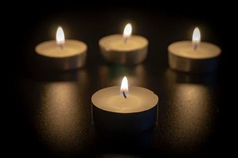 Four tea candles with reflection on black Stock Photos