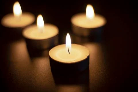 Four tea candles with reflection on black Stock Photos