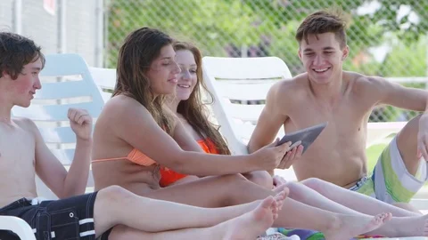Four teenagers using a tablet by the poolside Stock-Footage 80134369