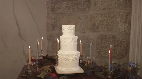 Four Tier White Wedding Cake with Candles and Autumn Leaves on Stone Wall 動画素材 332947953