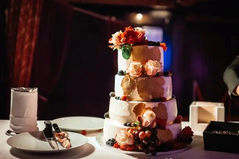 Four-tiered wedding cake on table in dark hall Stock Photos