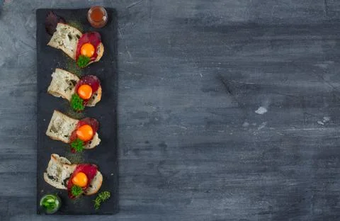 Four tiny appetizers with cured met, yolk and parmegano cheese on stone board Stock Photos