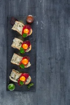 Four tiny appetizers with cured met, yolk and parmegano cheese on stone board Stock Photos