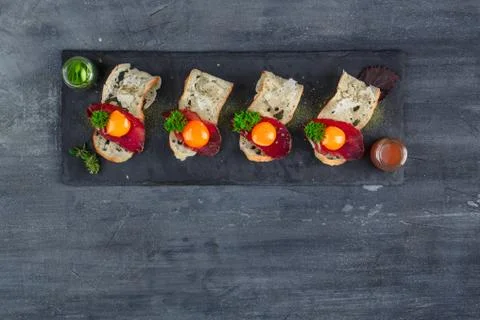 Four tiny appetizers with cured met, yolk and parmegano cheese on stone board Stock Photos