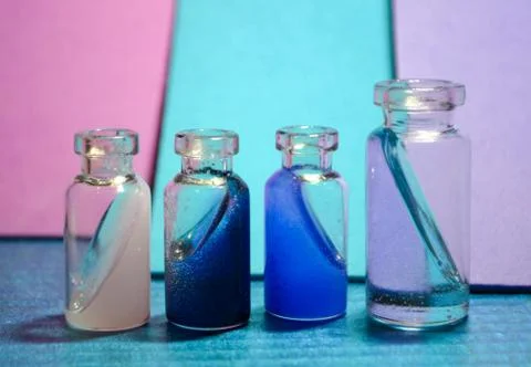 Four tiny bottles with magical liquid on colorful background Stock Photos
