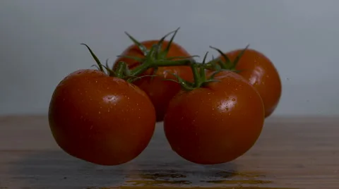 Four tomatoes are dropped onto a cutting board in slow motion and bounce Stock Footage 64336105