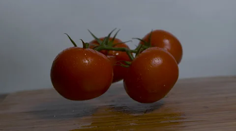 Four tomatoes fall onto a cutting board in slow motion rotating shot Stock Footage 64331270