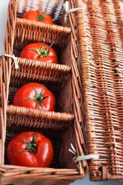 Four tomatoes in wicker box Stock Photos