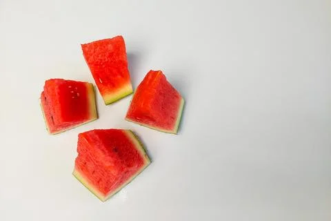 Four triangular slices of watermelon with bright red flesh on a white backg.. Stock Photos
