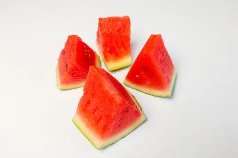 Four triangular slices of watermelon with bright red flesh on a white backg.. Stock Photos