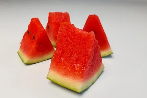 Four triangular slices of watermelon with bright red flesh on a white backg.. Stock Photos