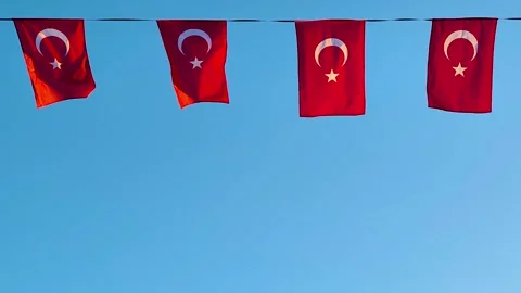 Four Turkish Flags Hanging Against a Bright Blue Sky Background Stock Footage 322996622