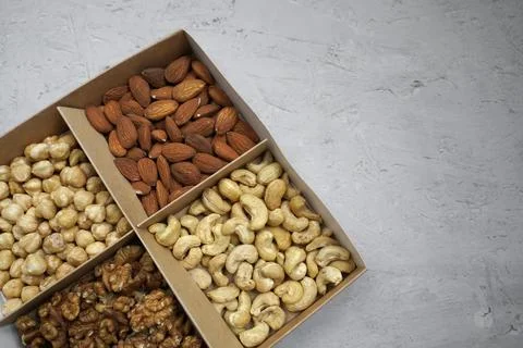 Four types of nuts in a paper box on a gray background with a blank space Fotos Stock
