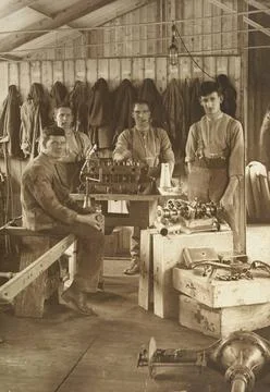 Four unidentified WWI working on an engine in a mechanical engineering wor... 库存照片