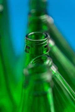 Four Vertical and three Diagonal Green Beer Bottles on a Blue Background Stock Photos