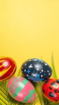 Four vibrantly hand-painted Easter eggs with various patterns rest on green.. 스톡 사진